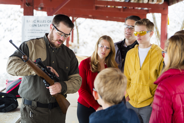 A group of people listening to an instructor at the gun range. Photographed on location at a shooting range.