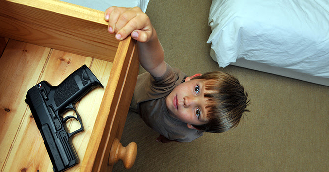 Boy (4-6 years old) reaching up to a bedroom drawer that contains a gun