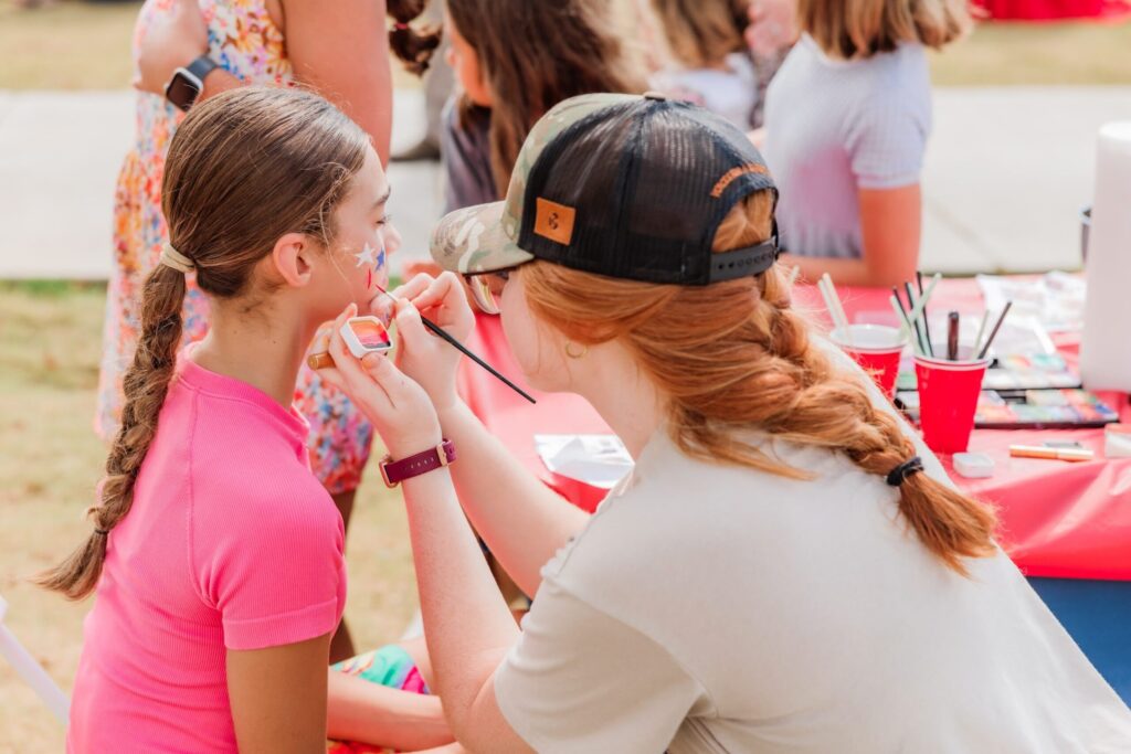 a volunteer paints the face of a young girl at a safer tn event